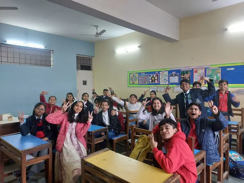 A classroom of students smiling and making peace signs